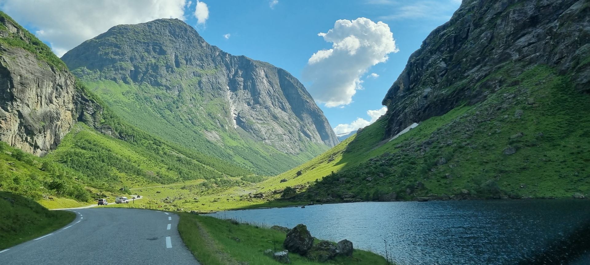 Road through Norangsdalen with steep mountains, water and green slopes