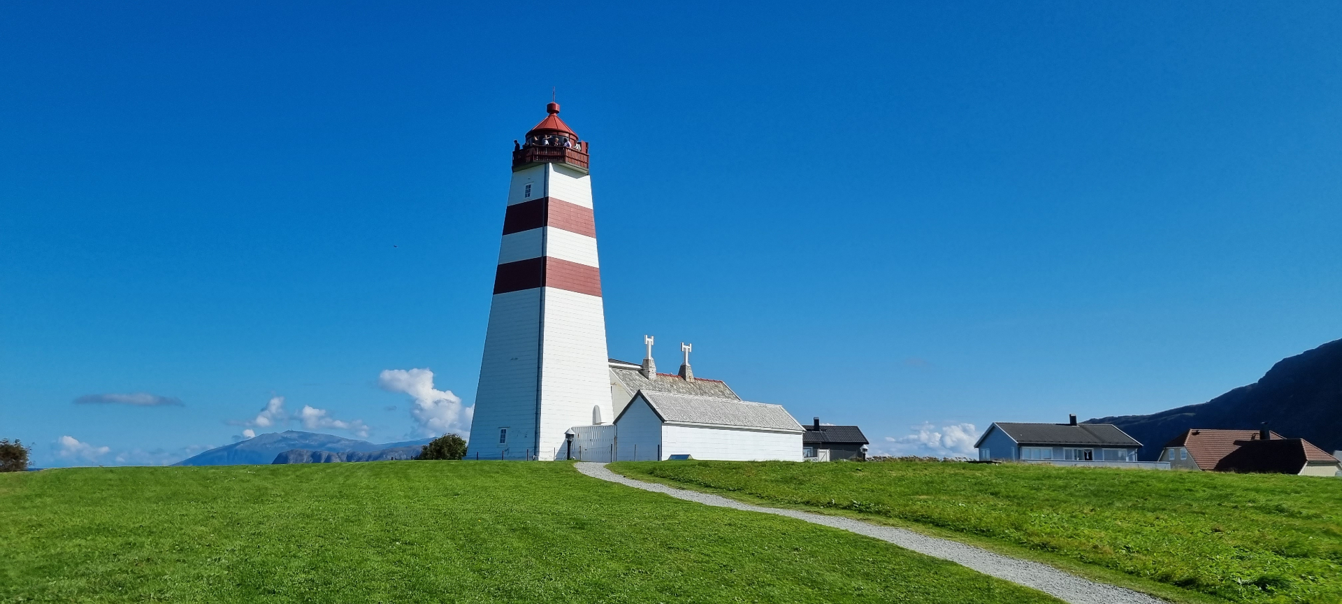 Alnes lighthouse with red and white stripes on a green hillside